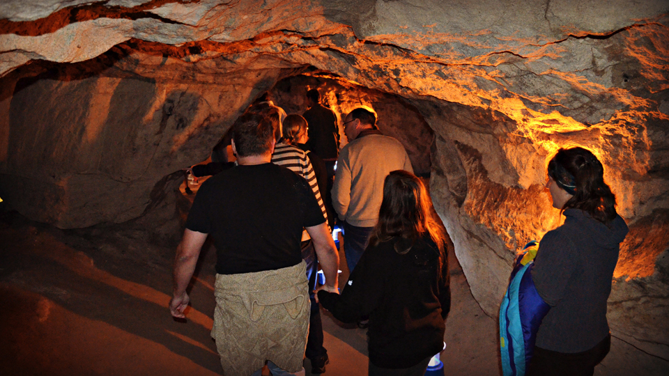 A group of people in different ages on a guided tour in the pillared halls down under in Tykarp´s cave. 