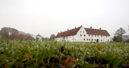 Hovdala slotts vita fina byggnader med rött tak och porttornet längst bort.