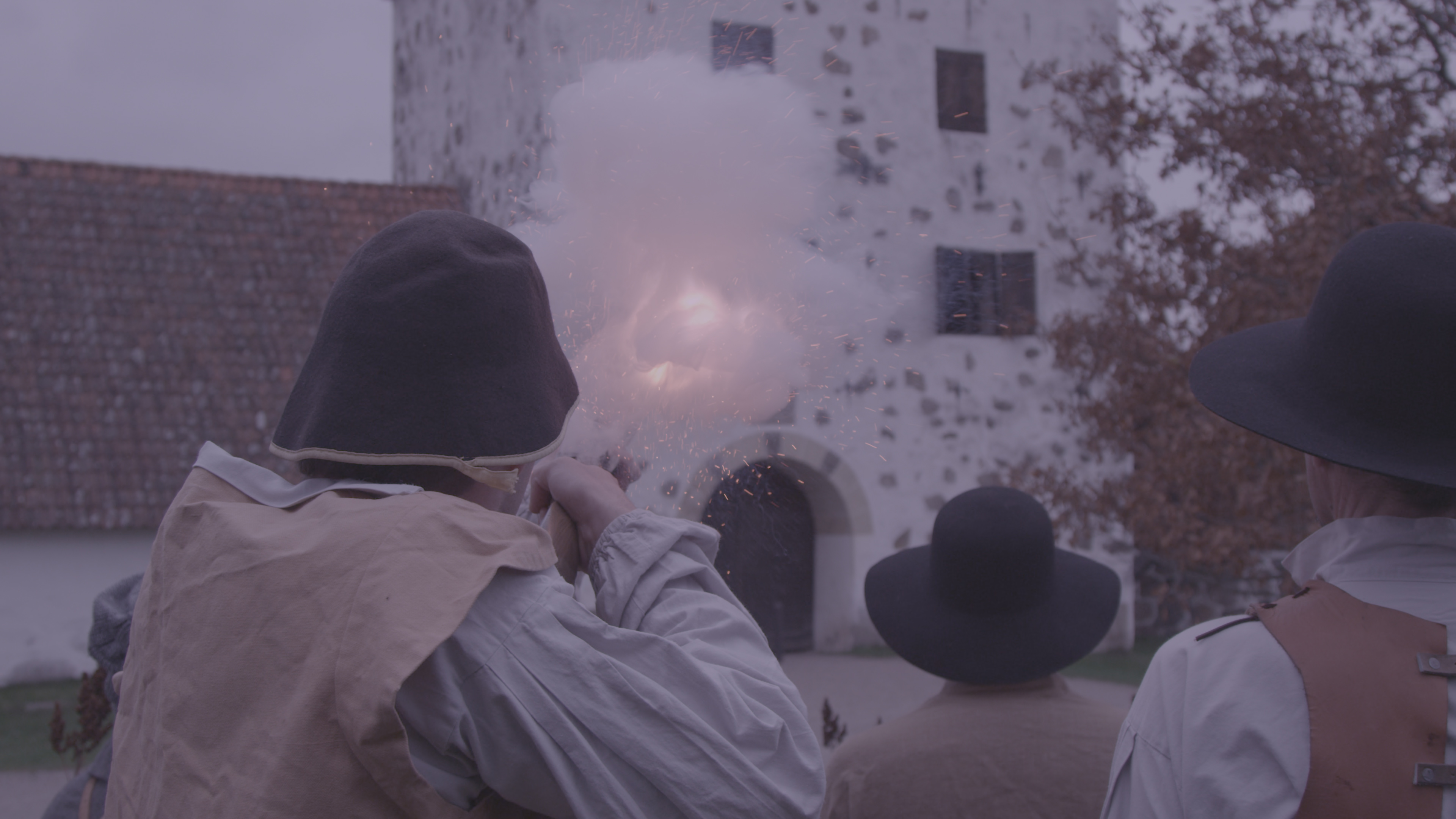 En man föreställande snapphane skjuter med sitt gevär i ett anfall mot porttornet på Hovdala slott (från en teaterscen)